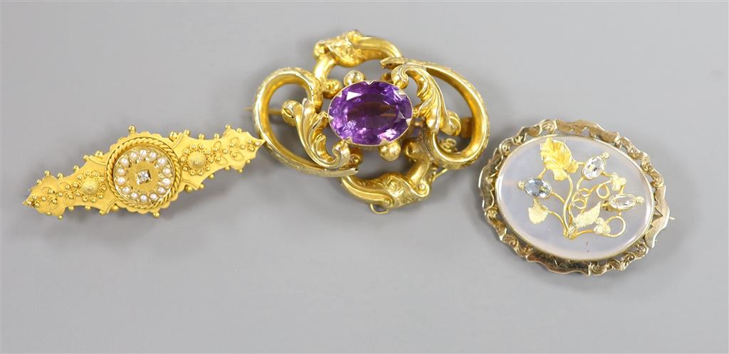 A Victorian yellow metal and amethyst set scroll brooch & 2 others.